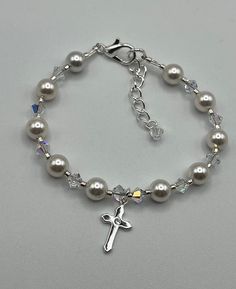 "This pretty bracelet is designed using white 6mm exquisite pearls, 4mm AB Austrian Crystal and a sterling silver cross with a cubic zirconia in the center!  This lovely bracelet is finished with a sterling silver plated lobster clasp and soldered jump ring.  A 1\" extender chain with a 4mm crystal dangle adds to this special piece! A wonderful keepsake for a Communion, Confirmation or Christening. If you have a special size request please let me know, always happy to help." Elegant Cross Beaded Bracelets As Gift, Elegant Cross-shaped Beaded Bracelets For Gift, Elegant Cross-shaped Beaded Bracelets As Gift, Elegant Silver Cross Beaded Bracelets, Elegant Silver Beaded Cross Bracelets, Elegant Rosary Bracelet With Round Beads For First Communion, Elegant Rosary Bracelet For First Communion With Round Beads, Elegant Rosary Bracelet With Round Beads For Baptism, Elegant Beaded Rosary Bracelet For First Communion