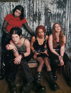 four women sitting on a bench in front of a wall with paint peeling off it