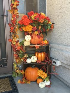 pumpkins, gourds and flowers are arranged on the front porch for fall