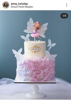 a birthday cake with a fairy on top and pink ruffles around the edges