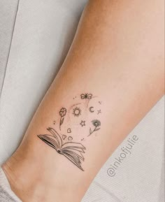 a person with a book tattoo on their arm and the pages are flying in the air