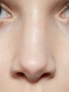 a woman's face with blue eyes and long eyelashes, close up on her nose