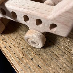 a wooden toy truck sitting on top of a wooden table next to a piece of wood