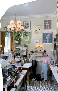 two women are standing at the counter in a coffee shop with posters on the wall