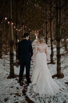 a bride and groom walking through the snow