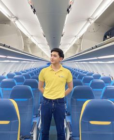 a man standing in the aisle of an airplane with blue seats and yellow trims