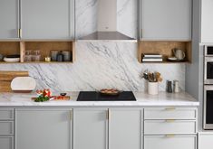 a kitchen with marble counter tops and gray cabinets