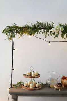 a table topped with cupcakes covered in frosted icing and greenery