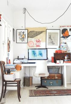 a room filled with lots of clutter and pictures hanging on the wall next to a desk