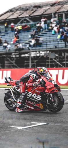 a man riding a motorcycle on top of a race track with people watching from the stands