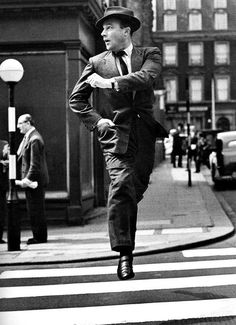 a man in a suit and hat is crossing the street