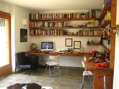 a home office with bookshelves and desk in front of the window, next to a cow hide rug