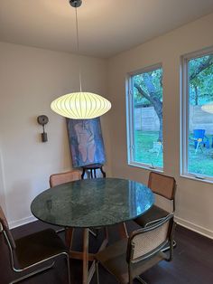 a table and chairs in a room with two large windows on the opposite side of the room