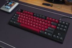 a red and black keyboard sitting on top of a desk