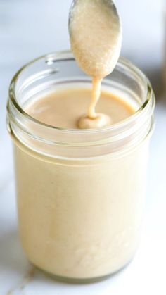 a spoon full of peanut butter on top of a jar