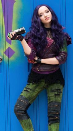 a woman with purple hair and green leggings posing in front of a blue door