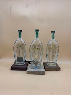 three glass bottles sitting on top of wooden bases