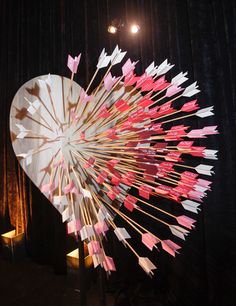 a large heart shaped sculpture with pink and white arrows sticking out of it's center