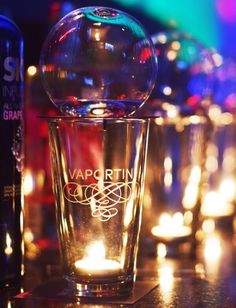 a shot glass sitting on top of a table next to some bottles and lights in the background