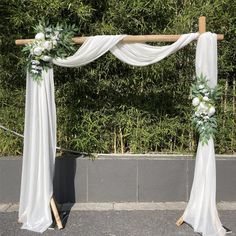 an outdoor wedding ceremony with white drapes and greenery