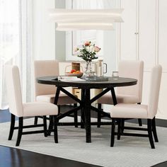 a dining room table with four chairs and a vase on top of the table in front of it