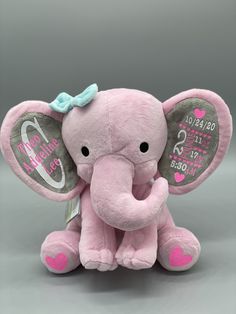 a pink stuffed elephant with a blue bow on its head and name written on it