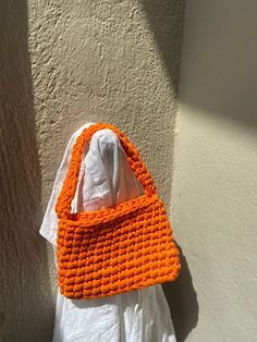 an orange crocheted purse hanging on a wall