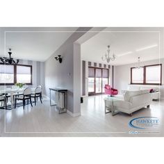 a living room filled with white furniture and lots of windows next to a dining table