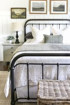 a bed with white linens and pillows in a small room next to two pictures on the wall