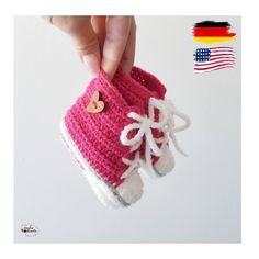 a hand is holding up a crocheted boot with a heart on the side