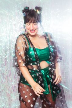 a woman in a green outfit with stars on her body and sheer stockings, smiling at the camera