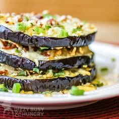 an eggplant dish is stacked on top of other food items and garnished with green onions