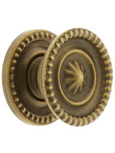 an antique brass door knob with a decorative design on the front and side, is shown