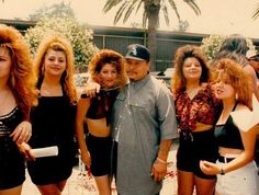 a group of people standing next to each other in front of a building with palm trees