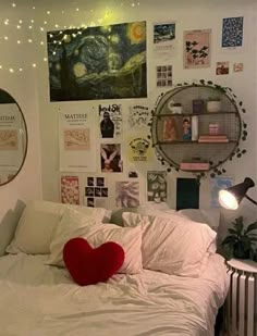 a bed with white sheets and pillows in a room filled with pictures on the wall