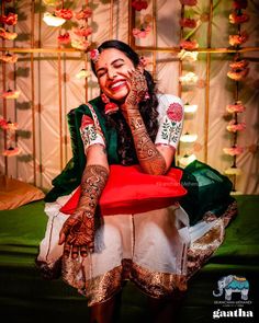 a woman sitting on top of a red chair covered in hendix and tattoos