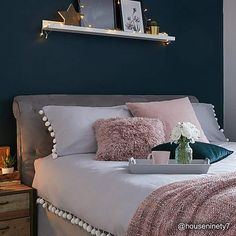 a bedroom with blue walls and white bedding, pink throw pillows on the bed