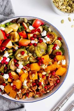 A colorful bowl of Brussels sprout salad topped with roasted butternut squash, Honeycrisp apple, pumpkin seeds, pomegranate, and goat cheese for a healthy fall-inspired meal.