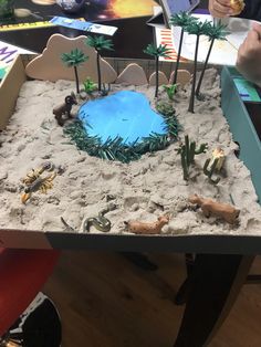 a desert scene made out of sand with animals and plants in the center, on top of a table