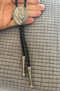 This awesome bolo tie has a pewter cowboy design. It is solid metal and heavy. Handmade in our shop! The cord is black and genuine leather. Our bolos pair nicely with many of our belt buckles! They make wonderful gifts.    The western bolo tie rope length is 39'' ;  pendant size is 1 1/4'' x 1 1/8'' Cowboy Jewelry Men, Vintage Black Jewelry For Western-themed Events, Southwestern Silver Bolo Tie For Rodeo, Southwestern Silver Bolo Ties For Rodeo, Vintage Bolo Ties With Adjustable Length For Rodeo, Silver Western Bolo Tie With Concho, Western Silver Bolo Ties For Western-themed Events, Vintage Silver Bolo Ties With Concho, Western Style Silver Bolo Ties For Western-themed Events