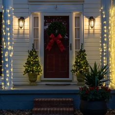 a red front door decorated with christmas lights