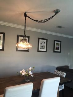 a dining room table with white chairs and pictures hanging on the wall above it,