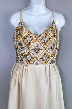 "This is a beautiful gown by the coveted label, Malcolm Starr. It is of what looks to be an ivory linen (may be rayon ) is fully lined, with a beaded bodice. There are a couple of missing beads on the back near zipper (picture) and maybe two or three on front neckline edge. There is also a stain on the back hemline. We have not attempted to treat. Estimated size S 2/4 36\" bust 25\" waist (tight 25\") 46\" hip 55\" shoulder to hem Know that whichever piece you choose to make your own has its own Vintage Embellished Silk Dress, Cream Sleeveless Evening Dress For Party, Cream Sleeveless Party Evening Dress, Cream Party Gown For Summer, Cream Summer Party Gown, Summer Party Cream Gown, Sleeveless Cream Gown For Party, Cream Party Gown With Fitted Bodice, Cream Sequin Dress For Formal Occasions