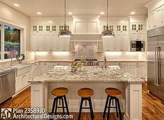 a large kitchen with white cabinets and marble counter tops, two stools at the island