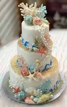 a three tiered cake decorated with seashells and starfish