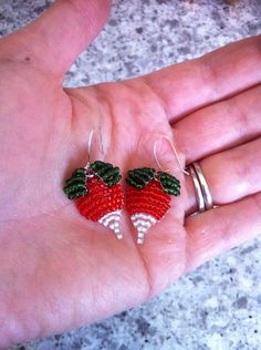 two red strawberries are being held in someone's hand with rings on it