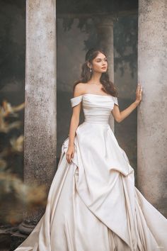 a woman in a white wedding dress standing next to columns