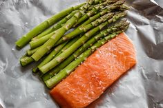 a piece of salmon and asparagus on aluminum foil, ready to be cooked