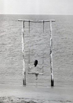 a woman sitting on a swing in the water