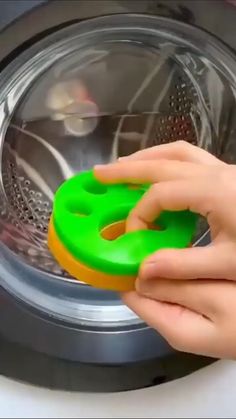 someone is holding two plastic objects in front of a washing machine